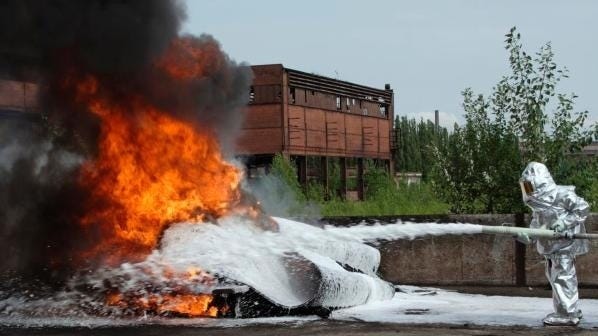 A firefighter sprays foam on a blaze.