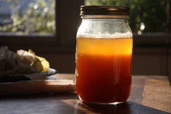 Jars of brightly coloured liquids in the process of making pigments. The yellow is bright in the morning sunlight. The pigment is heavy at the bottom of the jars with a gradient of colour.