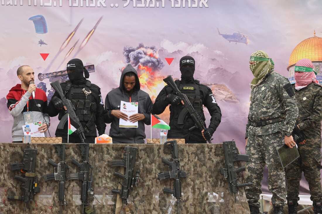 Israeli hostages Averu Mengistu (4th-R) and Tal Shoham (L) are flanked by Hamas fighters as they stand on a stage during their release in Rafah in the southern Gaza Strip on Saturday. Israeli hostages Averu Mengistu (4th-R) and Tal Shoham (L) are flanked by Hamas fighters as they stand on a stage during their release in Rafah in the southern Gaza Strip on Saturday.