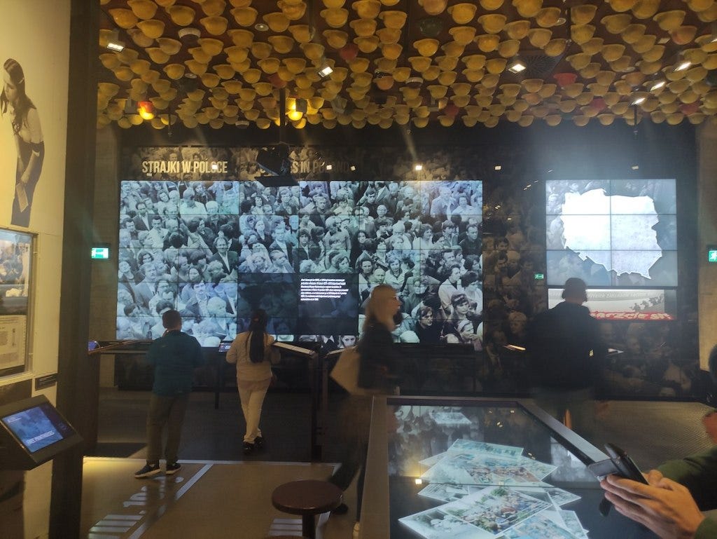 A large video wall shows protests. There is a tablet to browse other information, and photographs of people involved in protests in a glass exhibition cabinet.