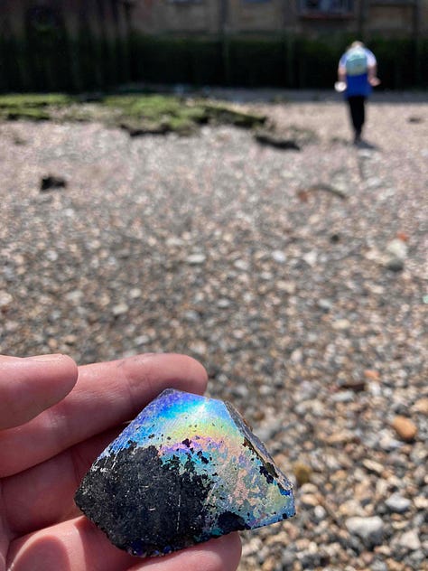 Women on the banks of the River Thames. She is mudlarking. The Shard buidling is in the background. The second image is of colourful piece of glass found in the mud. The third image shows pebbles with many rusty nails and pieces of metal from scrapped sailing vessels.