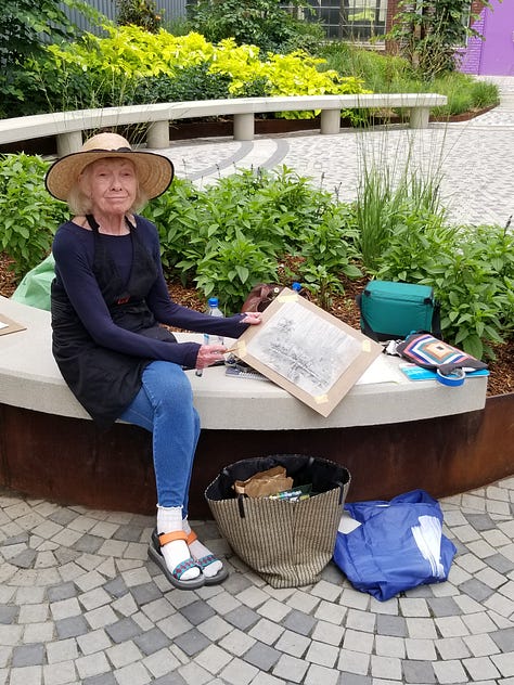 People sketching in an urban courtyard surrounded by flowers and other plants in beds.