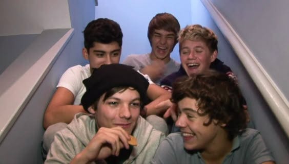 This may contain: five young men are sitting on the stairs and eating food in front of their faces