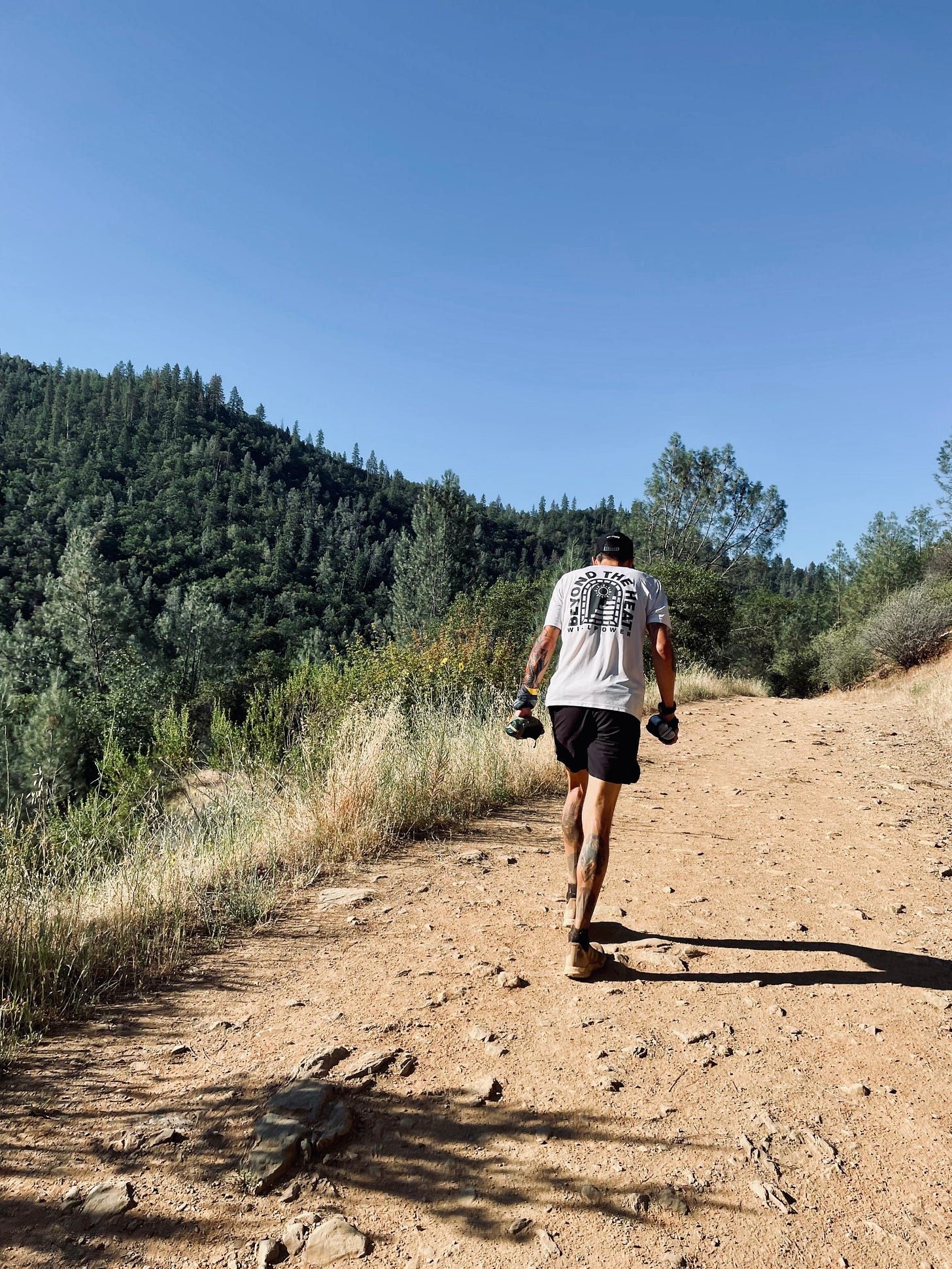 the author hiking up a dusty trail with 2 hand bottles at the western states endurance run 2022
