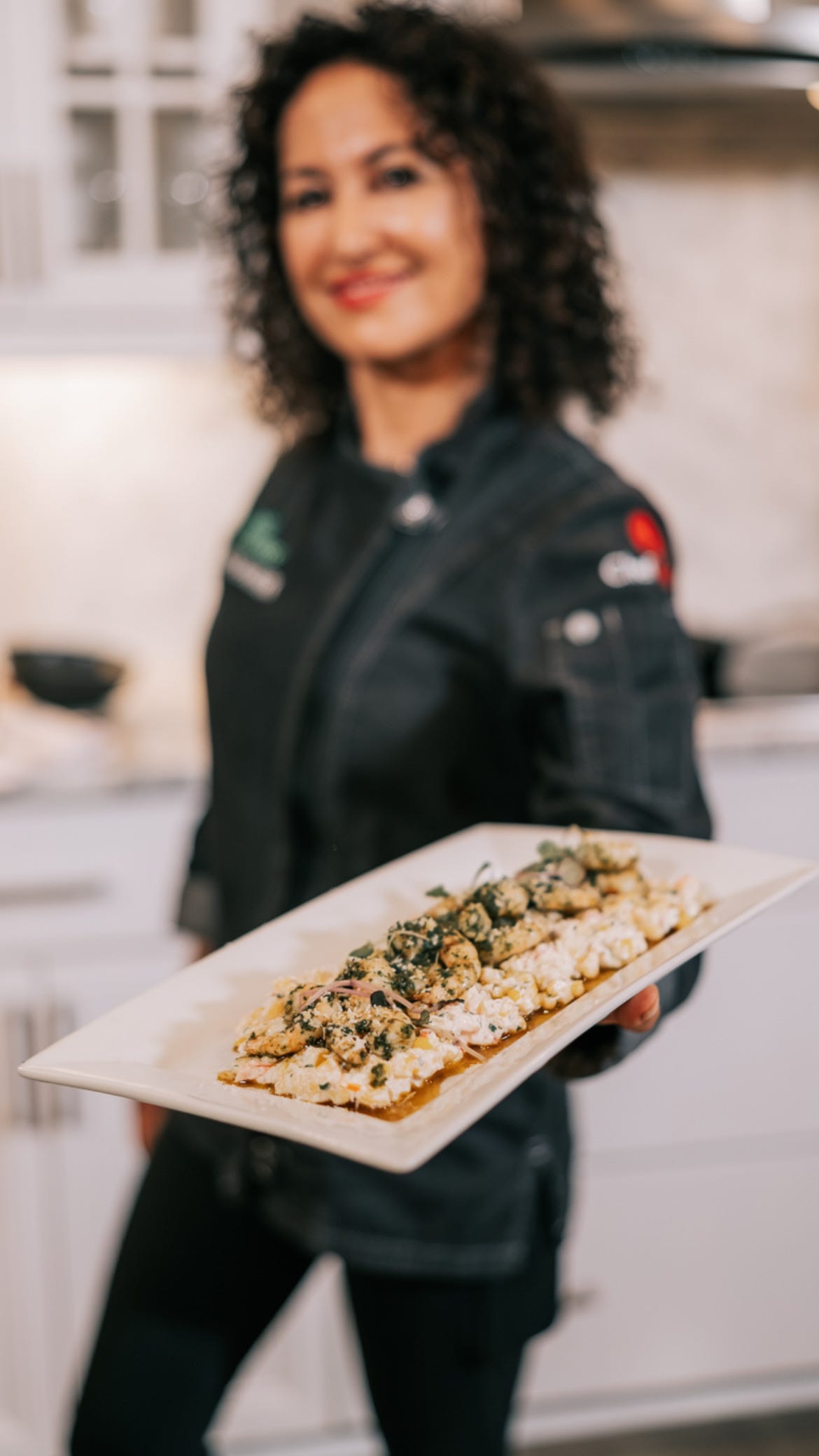 Chef Mareya presenting her pan seared shrimp with chermoula and ricotta corn salad on a white plate