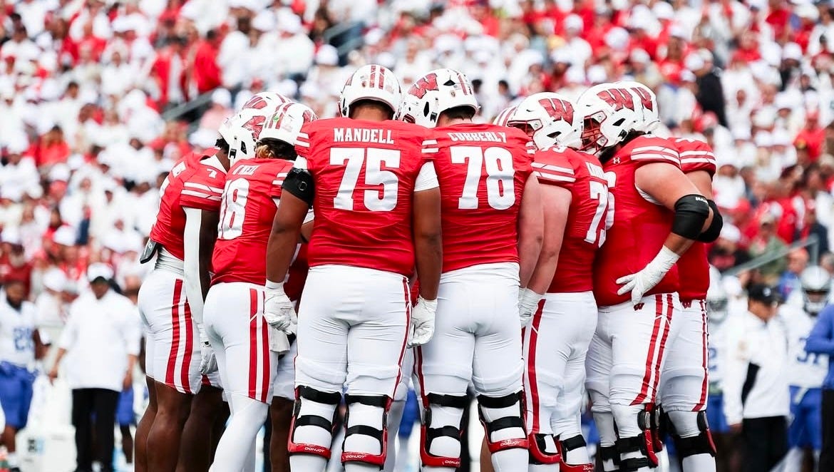 Wisconsin Badgers offensive players huddle together before a play during a game.