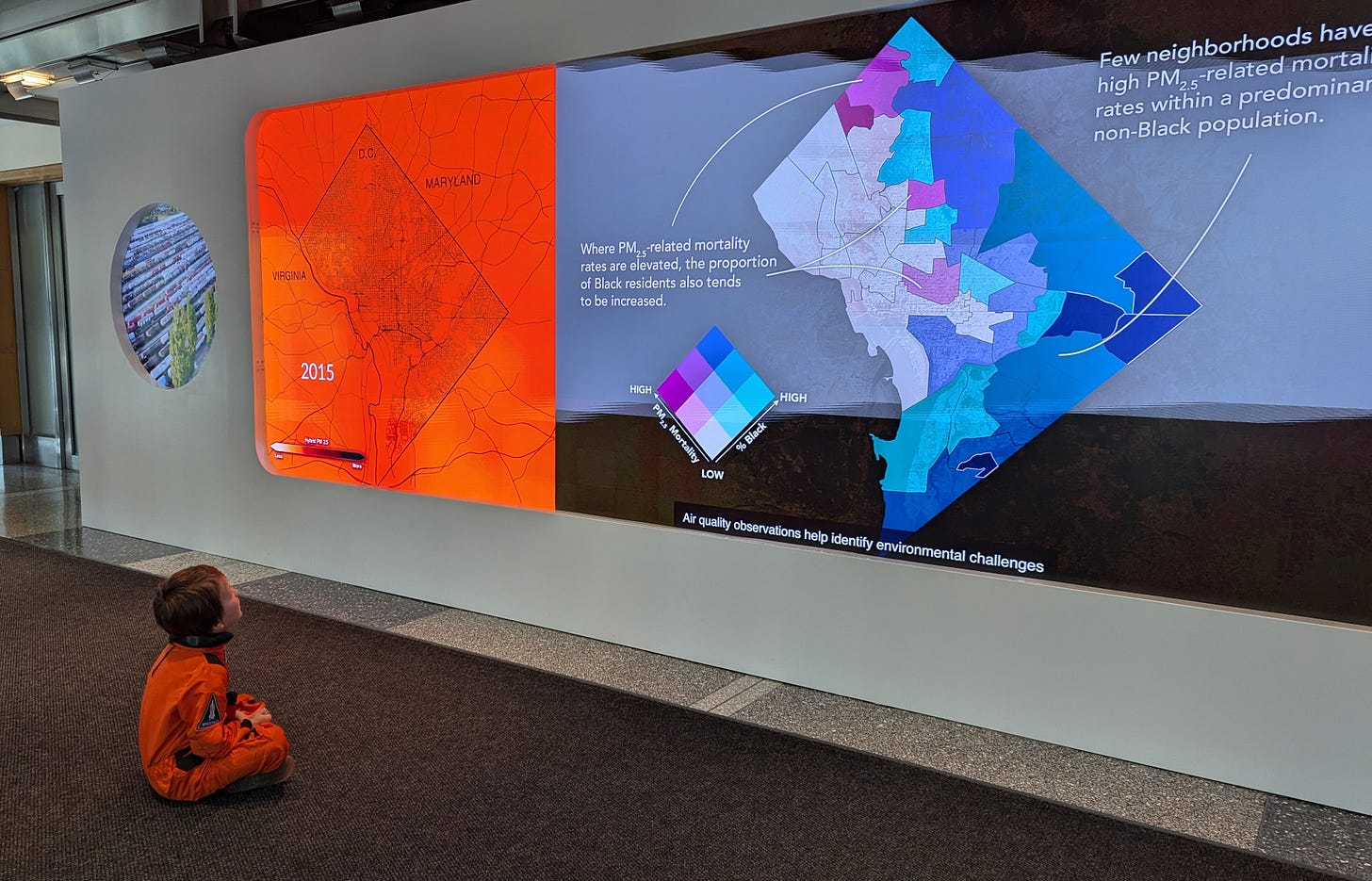 Child in orange astronaut costume sitting in front of a screen with maps Child in orange astronaut costume sitting in front of a screen with maps