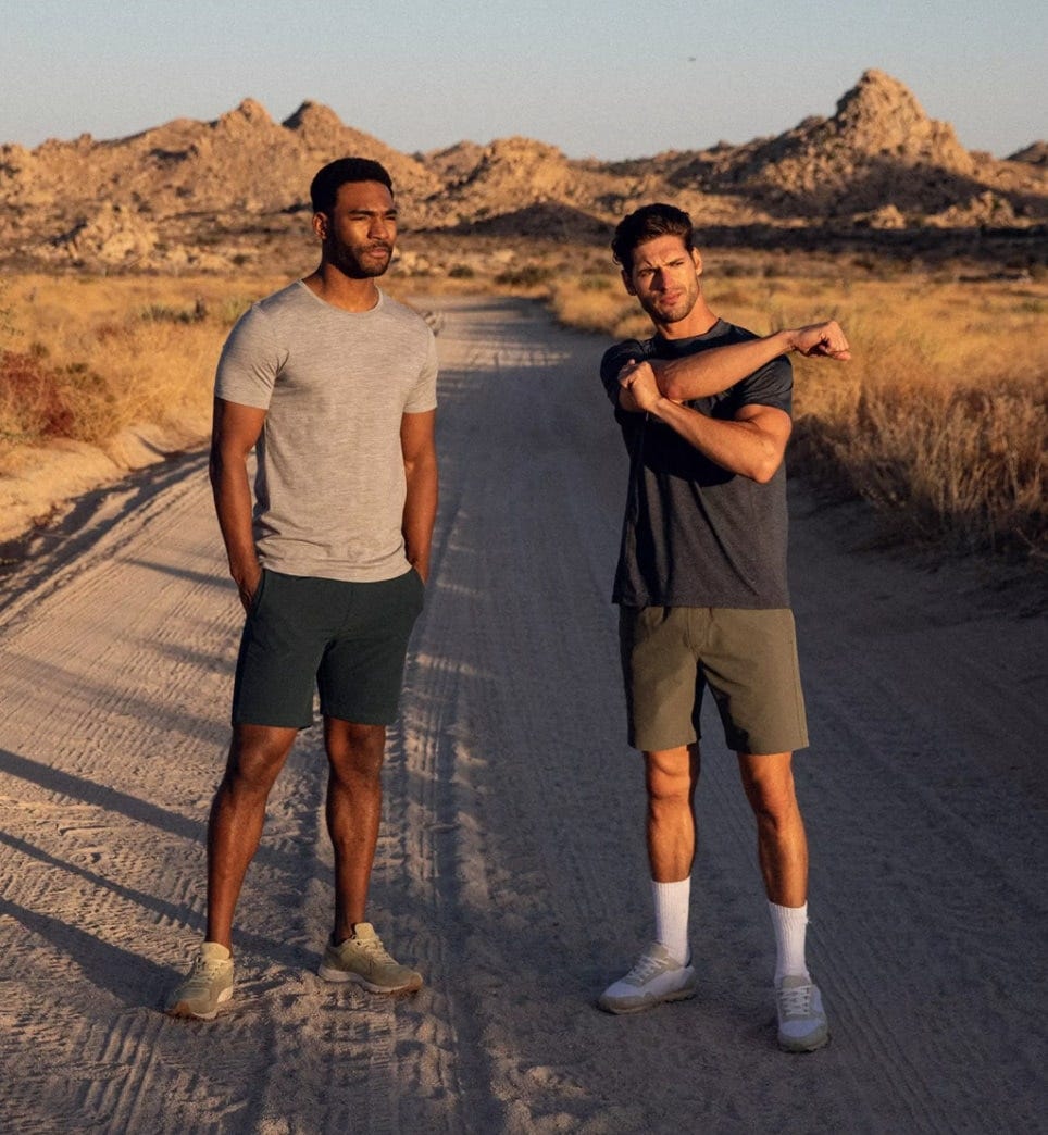 two men wearing olivers all over shorts stretch their muscles for a sunset run