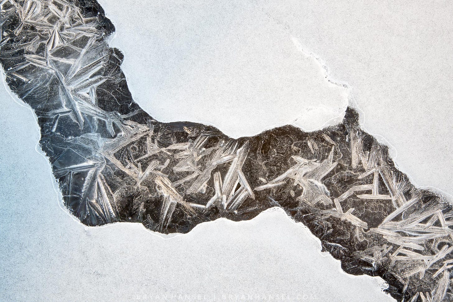 a frozen wave pool with white ice surrounding a crack of clear ice with ice crystals in it