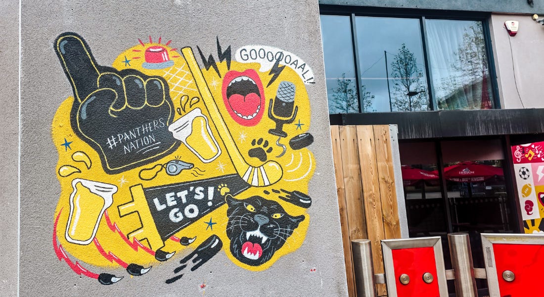 A wall with yellow and black Nottingham Panthers street art on it, and a black and red bar building to the right of it