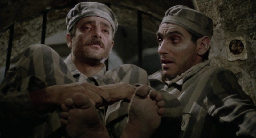 A still frame from Lina Wertmüller's 1975 Oscar-nominated movie Seven Beauties. Two Italian men wearing prison outfits stare into the distance.