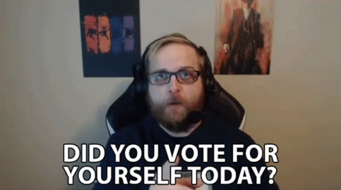 a man with a beard and glasses is sitting in a chair with a microphone and says did you vote for yourself today .