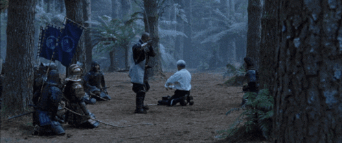 a man in a white shirt is kneeling down next to a man in armor with a sword a man in a white shirt is kneeling down next to a man in armor with a sword