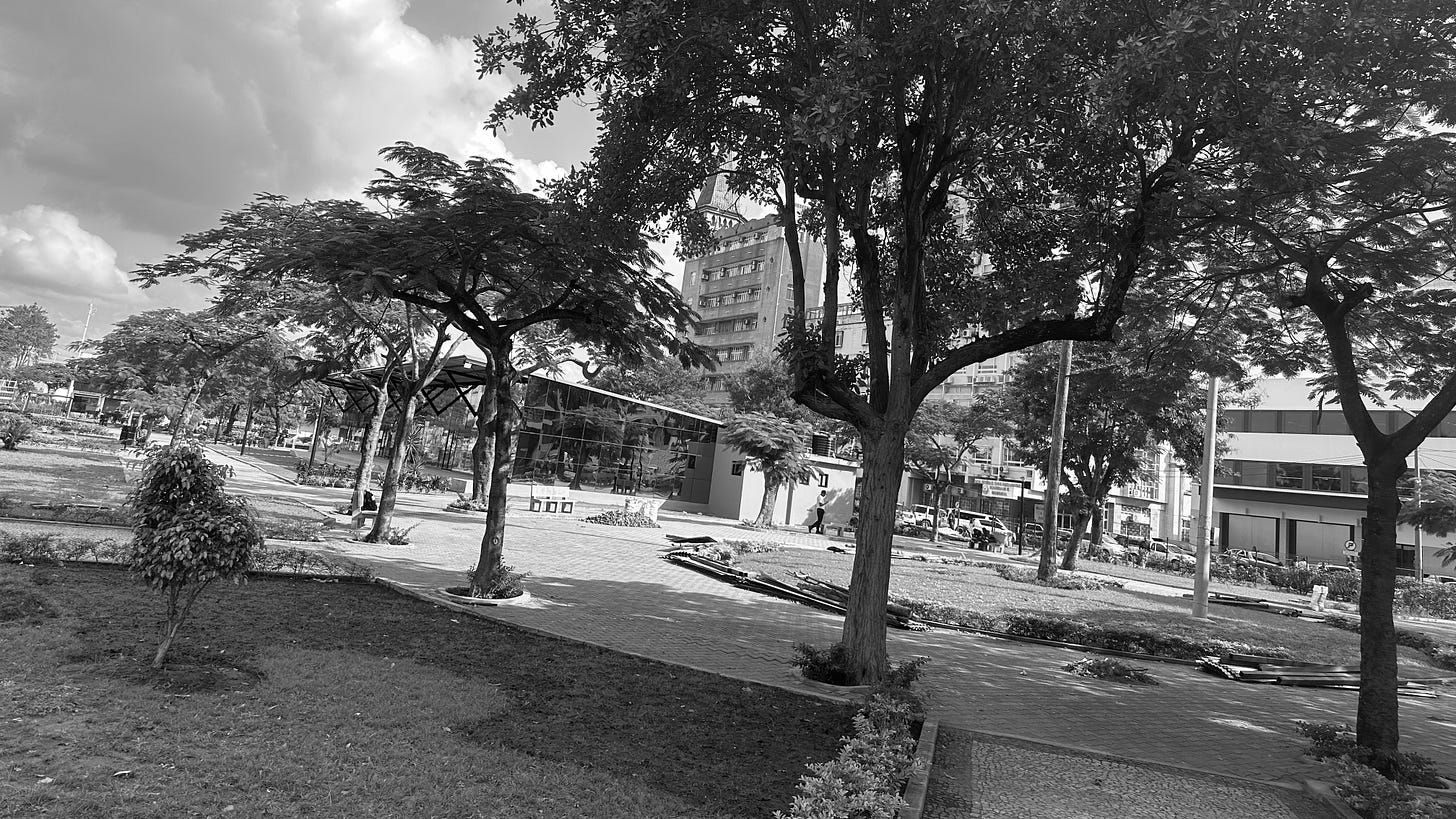 The picture shows a small square, with trees and a small service station The picture shows a small square, with trees and a small service station