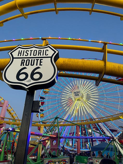 the pier sign, the pacific park sign, the end of route 66 sign, and the sun setting and rising over the pier
