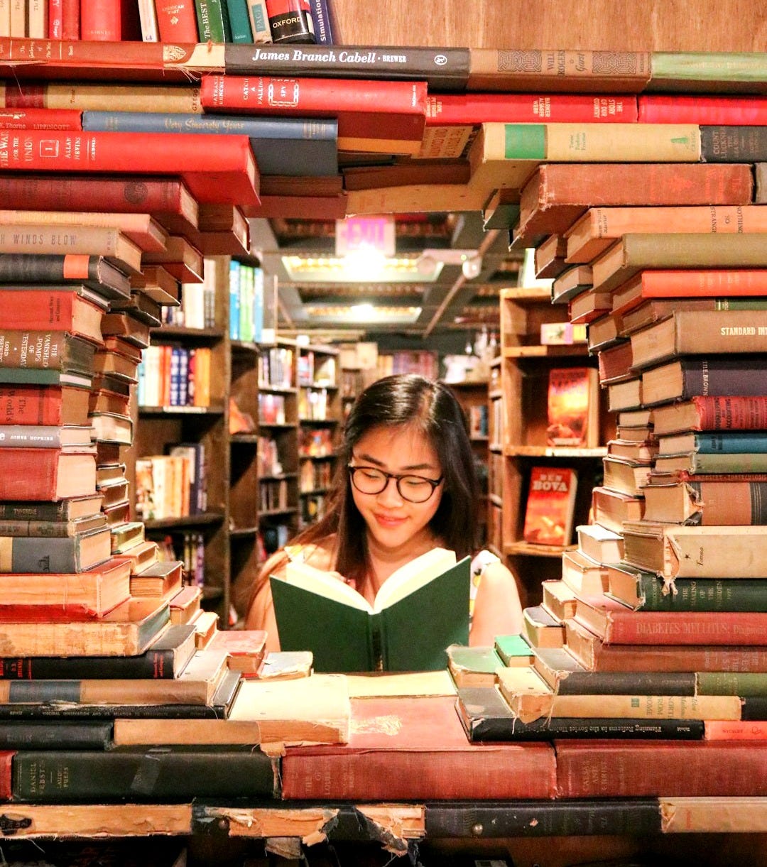 woman in green shirt sitting on books
