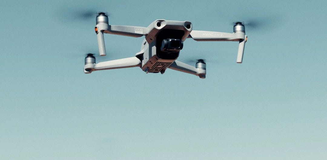 black and white drone flying under blue sky during daytime