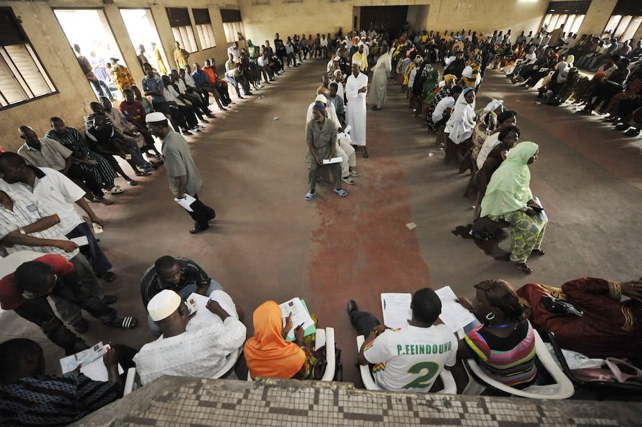 People sitting on a queue inside a hall People sitting on a queue inside a hall
