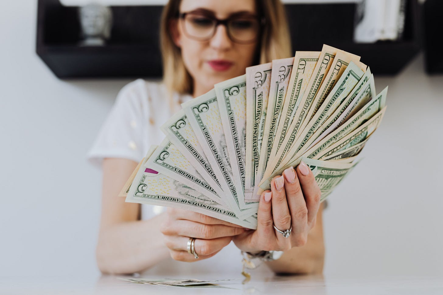 Close-up of a woman holding and fanning U.S. dollar bills indoors. Close-up of a woman holding and fanning U.S. dollar bills indoors.