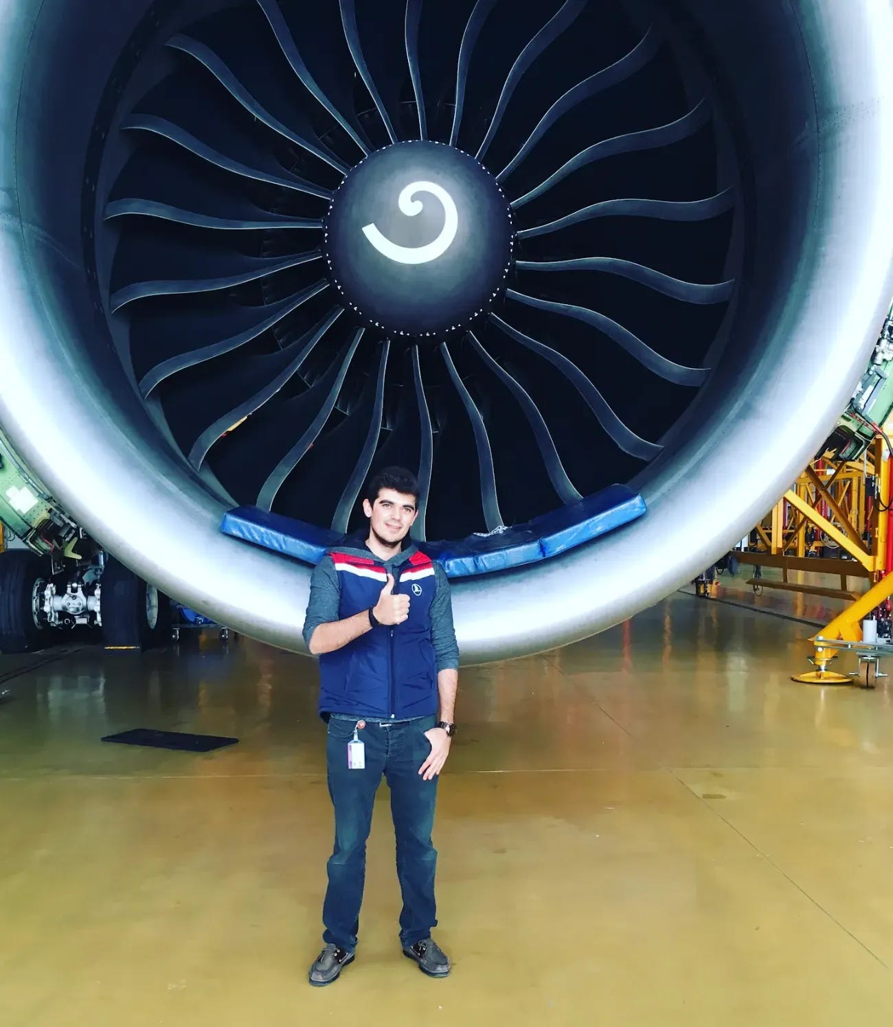 Gencay in front of a jet engine, from his years as an engineer before AI work