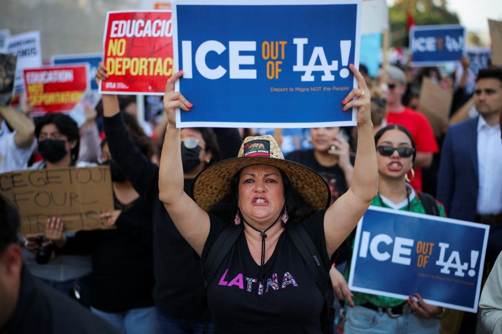 Protestors holding signs that read "ICE OUT OF LA!" at a demonstration in Los Angeles.