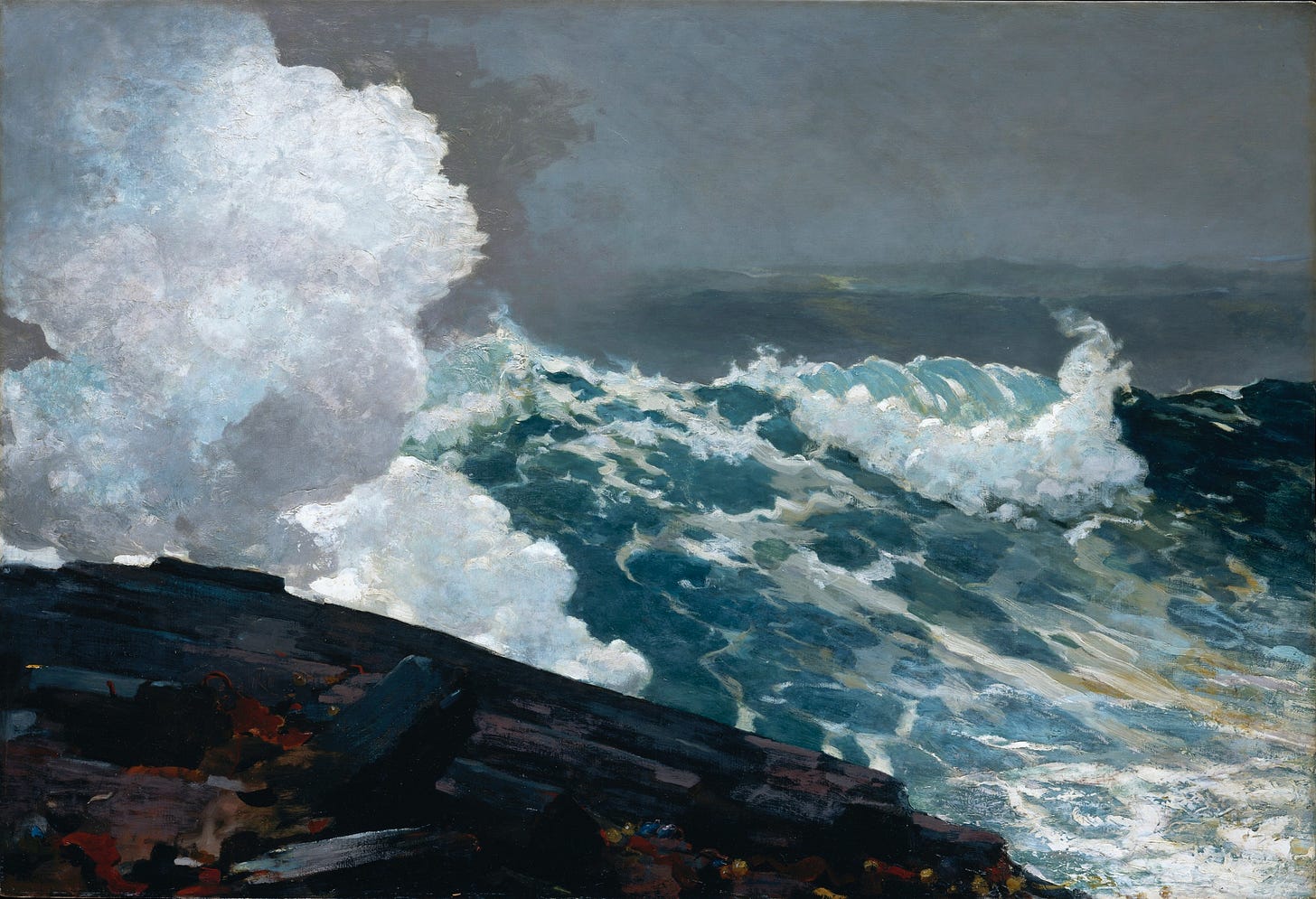 A huge wave explodes in white spray against dark rocks under a heavy grey sky A huge wave explodes in white spray against dark rocks under a heavy grey sky