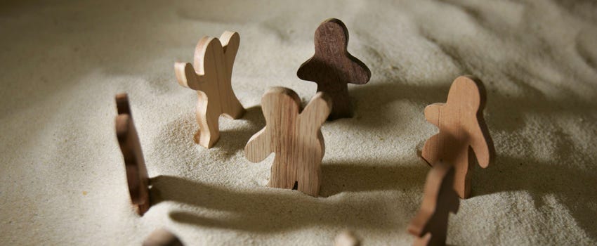 Wooden people of God figures are arranged in the sand that symbolizes the desert of the Old Testament.