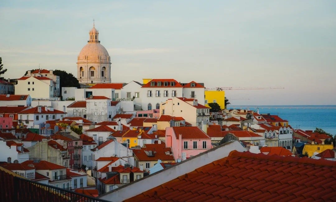 Terracotta rooftops of Lisbon’s Alfama at golden hour, the Panteão Nacional dome behind, the Tejo on the horizon Terracotta rooftops of Lisbon’s Alfama at golden hour, the Panteão Nacional dome behind, the Tejo on the horizon