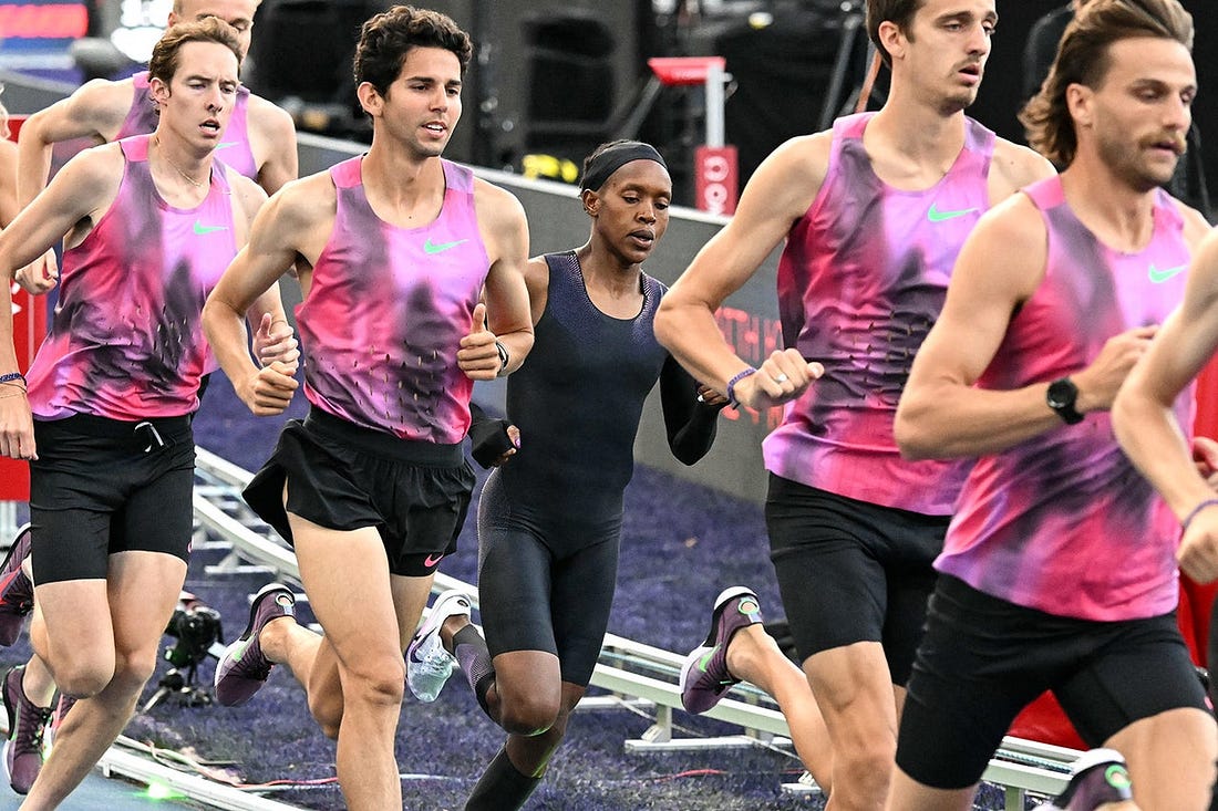 One woman, Faith Kipyegon, running behind a crowd of male pacers. 