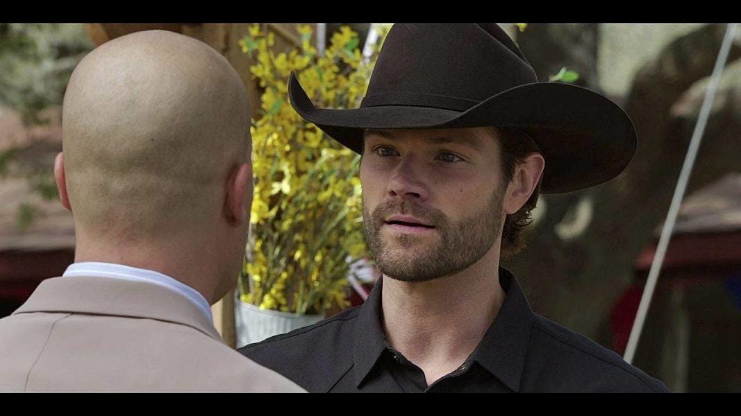 Walker Jared Padalecki in black hat looking intently at Cody Bell. Walker Jared Padalecki in black hat looking intently at Cody Bell.