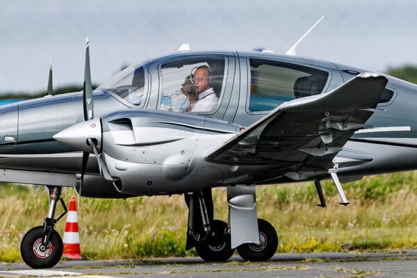A pilot and passenger in a small silver plane.