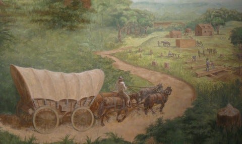 A pair of horses pulling a covered wagon through the wilderness