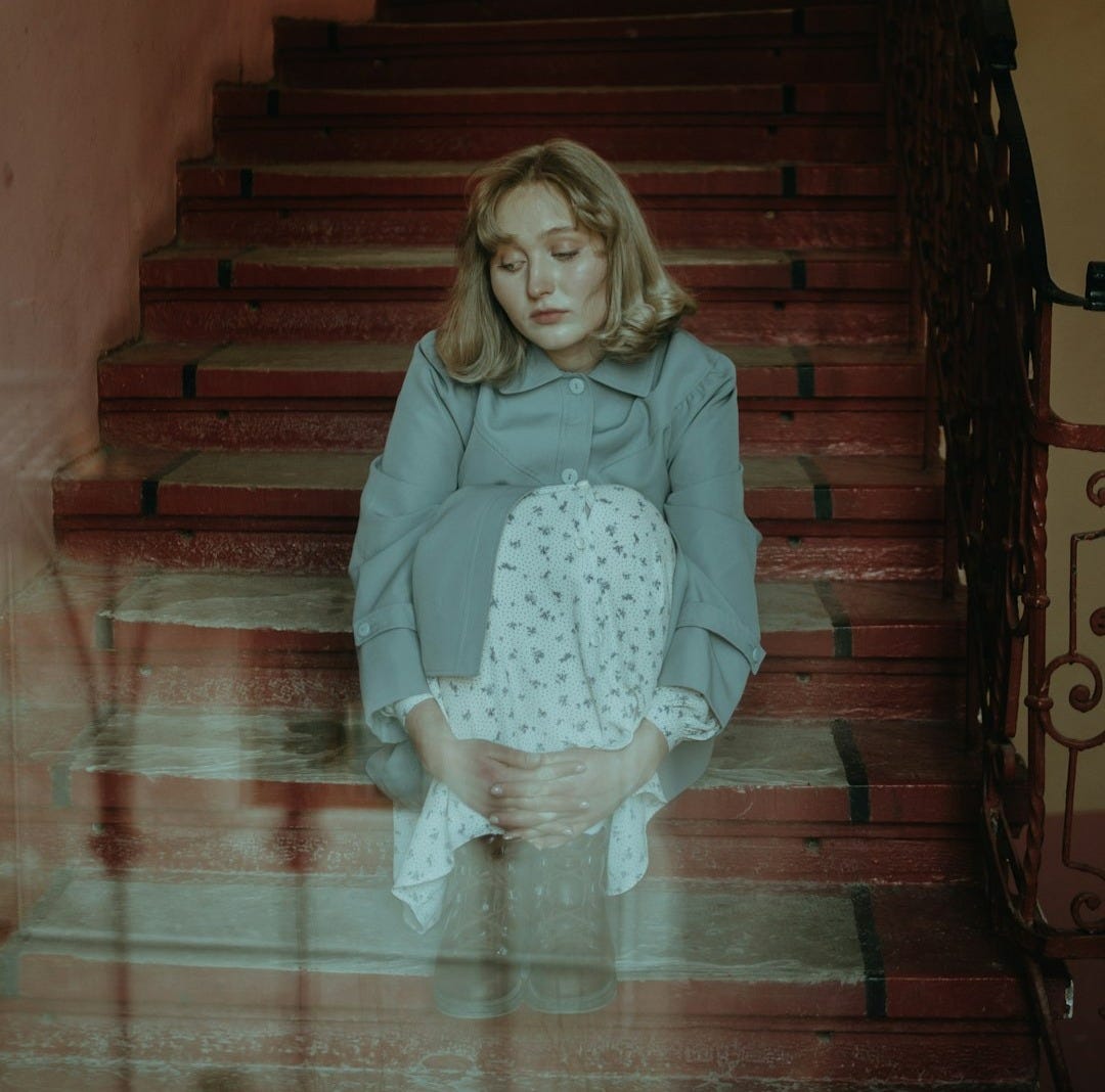 girl in pink long sleeve shirt and white skirt sitting on brown wooden staircase