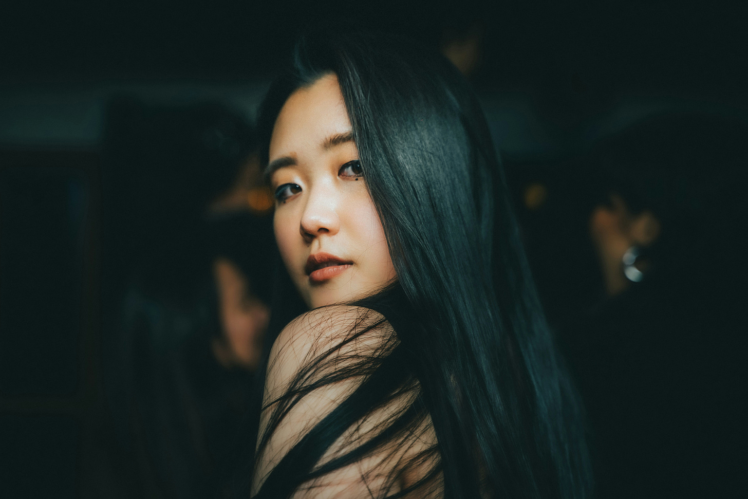 Woman, long black hair, looking back over bare shoulder