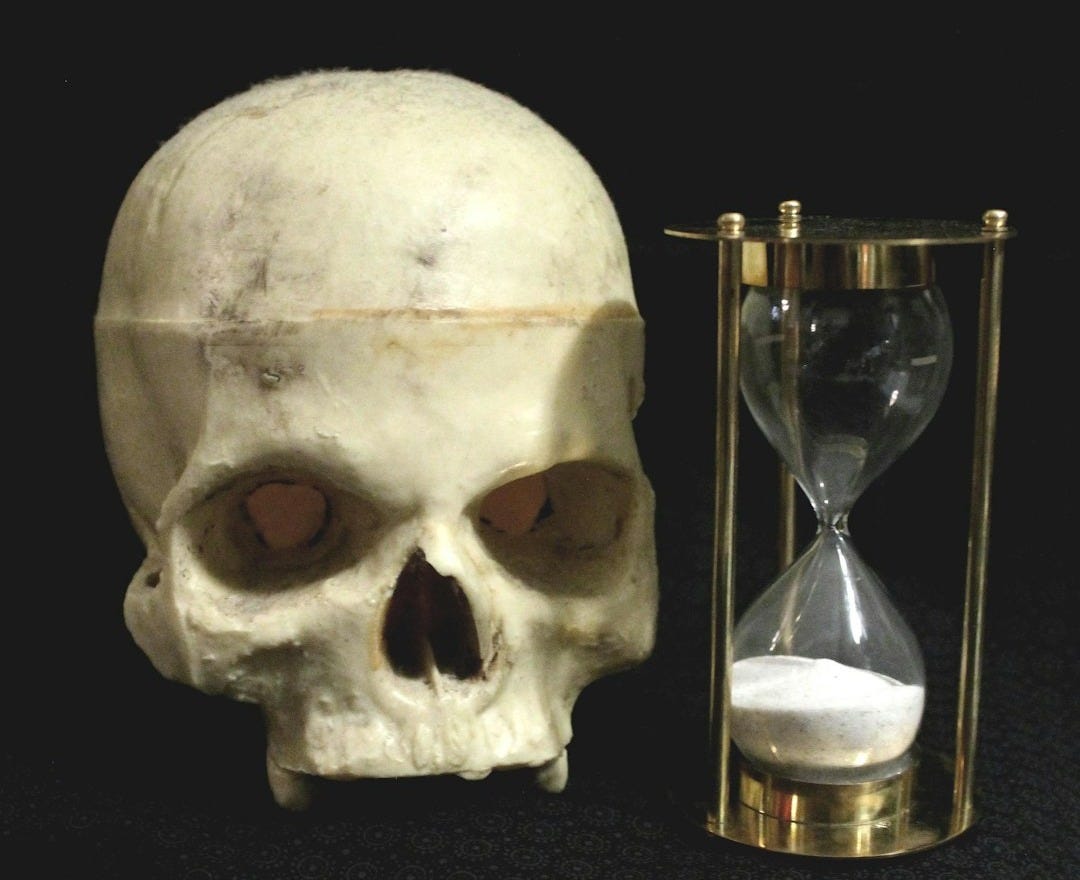 a human skull next to an hourglass