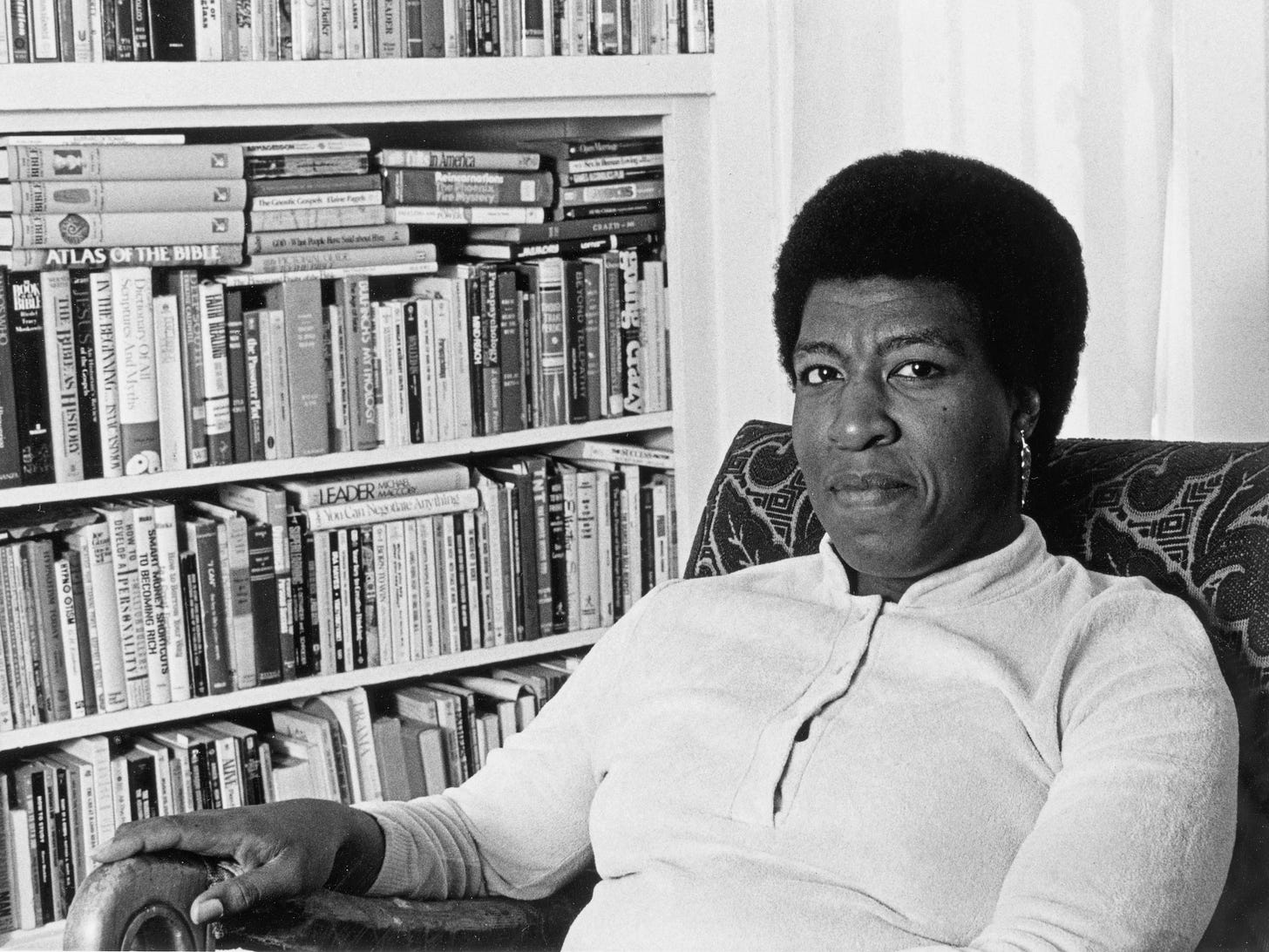 Octavia Butler sitting on a chair on front of a bookshelf