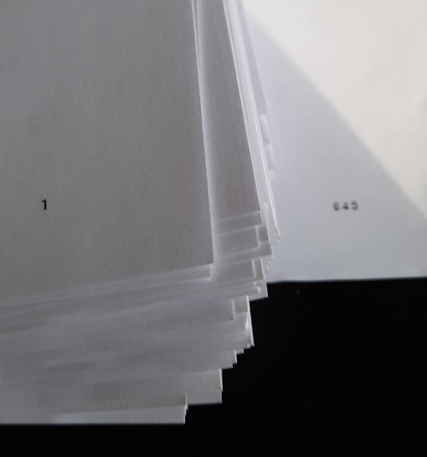 The corner of a pile of papers. The top page is number 1 and the bottom is numbered 645.