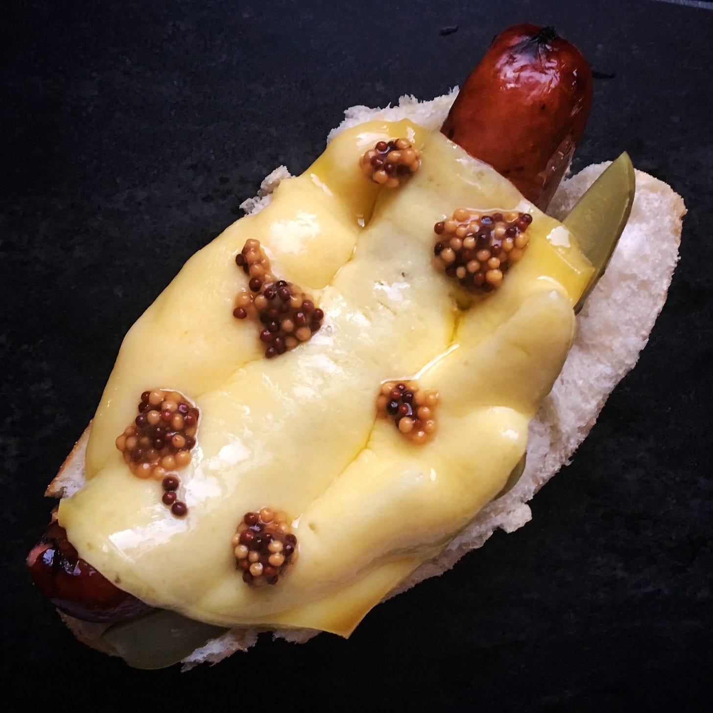 Sausage in a bun with raclette, mustard, and pickles Sausage in a bun with raclette, mustard, and pickles