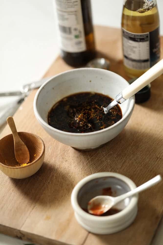 A small bowl with orange chicken sauce being whisked together.