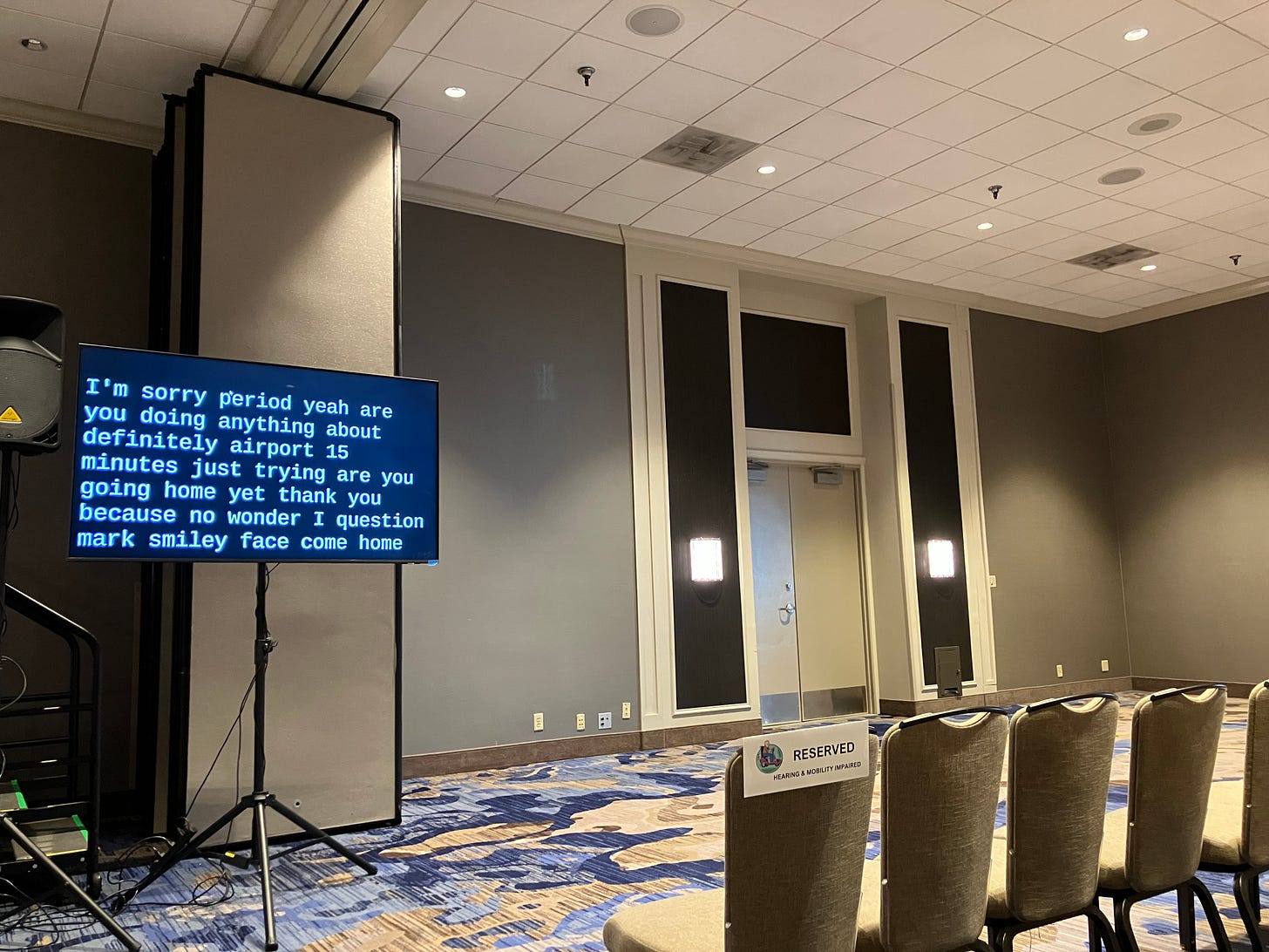 photo of conference room with empty seats and audio transcription screen