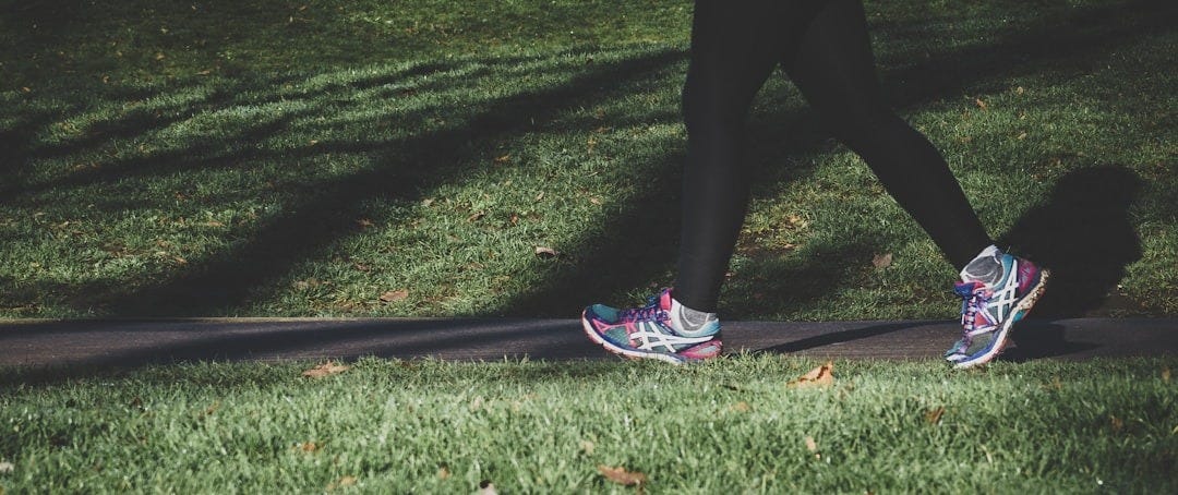 shallow focus photography of person walking on road between grass