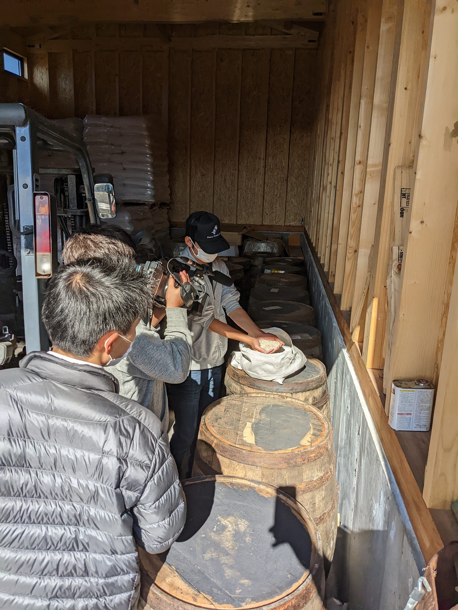 Television crew with cameras and equipment filming whisky barrels in Rishiri distillery warehouse