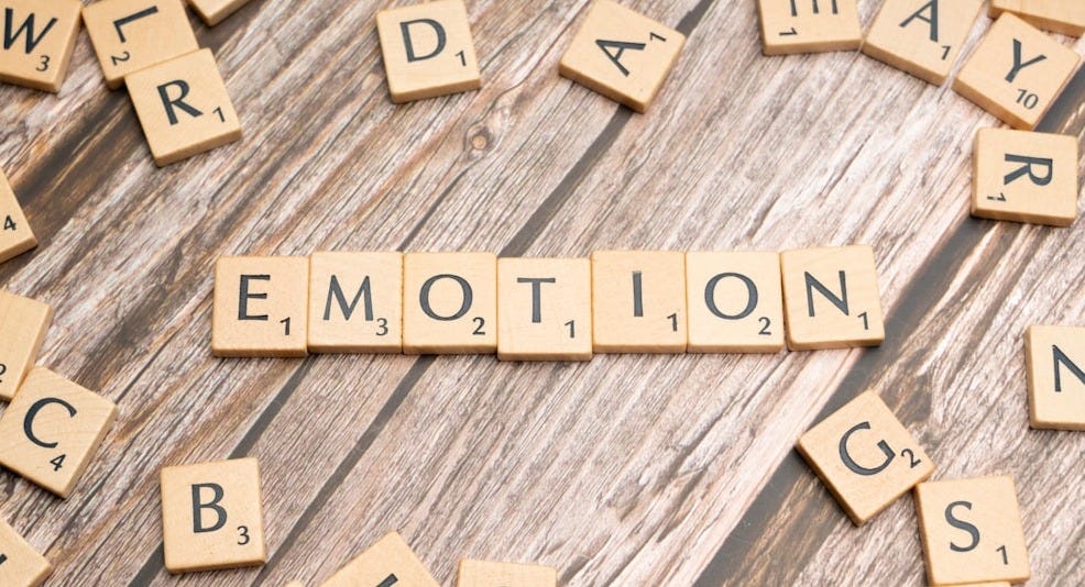 scrabble tiles spelling the word emotion on a wooden surface scrabble tiles spelling the word emotion on a wooden surface