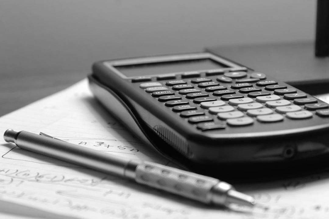 a calculator and a pen sitting on top of a piece of paper a calculator and a pen sitting on top of a piece of paper