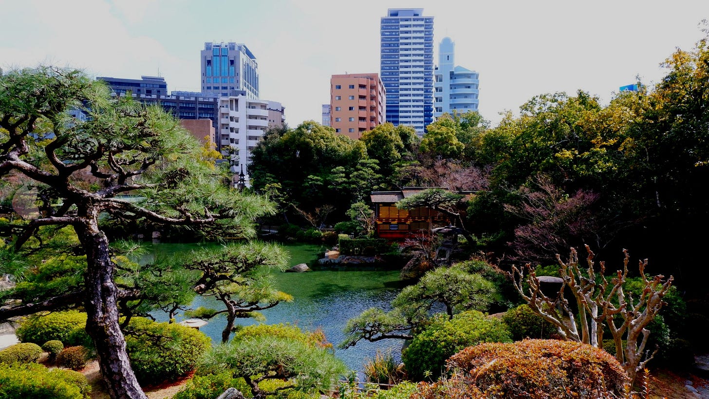 View overlooking a traditional Japanese garden with manicured greenery, framed by Kobe’s modern skyscrapers in the distance. View overlooking a traditional Japanese garden with manicured greenery, framed by Kobe’s modern skyscrapers in the distance.