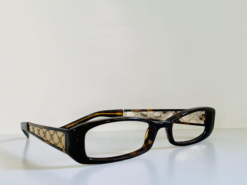 May include: A pair of tortoiseshell eyeglasses with a rectangular frame and clear lenses.