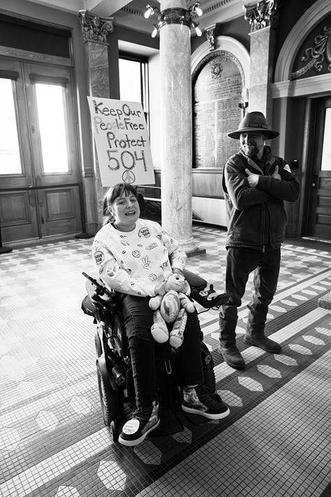A gallery of black and white photos of a rally in the rotunda of Montana's state capitol. people are holding signs in support of disability rights, there is a podium with legislators speaking, people with a virety of physical disabilities are throughout the crowd.
