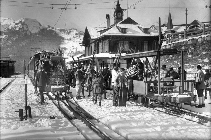 This may contain: an old black and white photo of people at a train station in the snow with mountains in the background