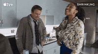 A gif from Shrinking. Jason Segel is doing the Home Alone shock face and Jessical Williams is throwing her hands in the air in celebration.