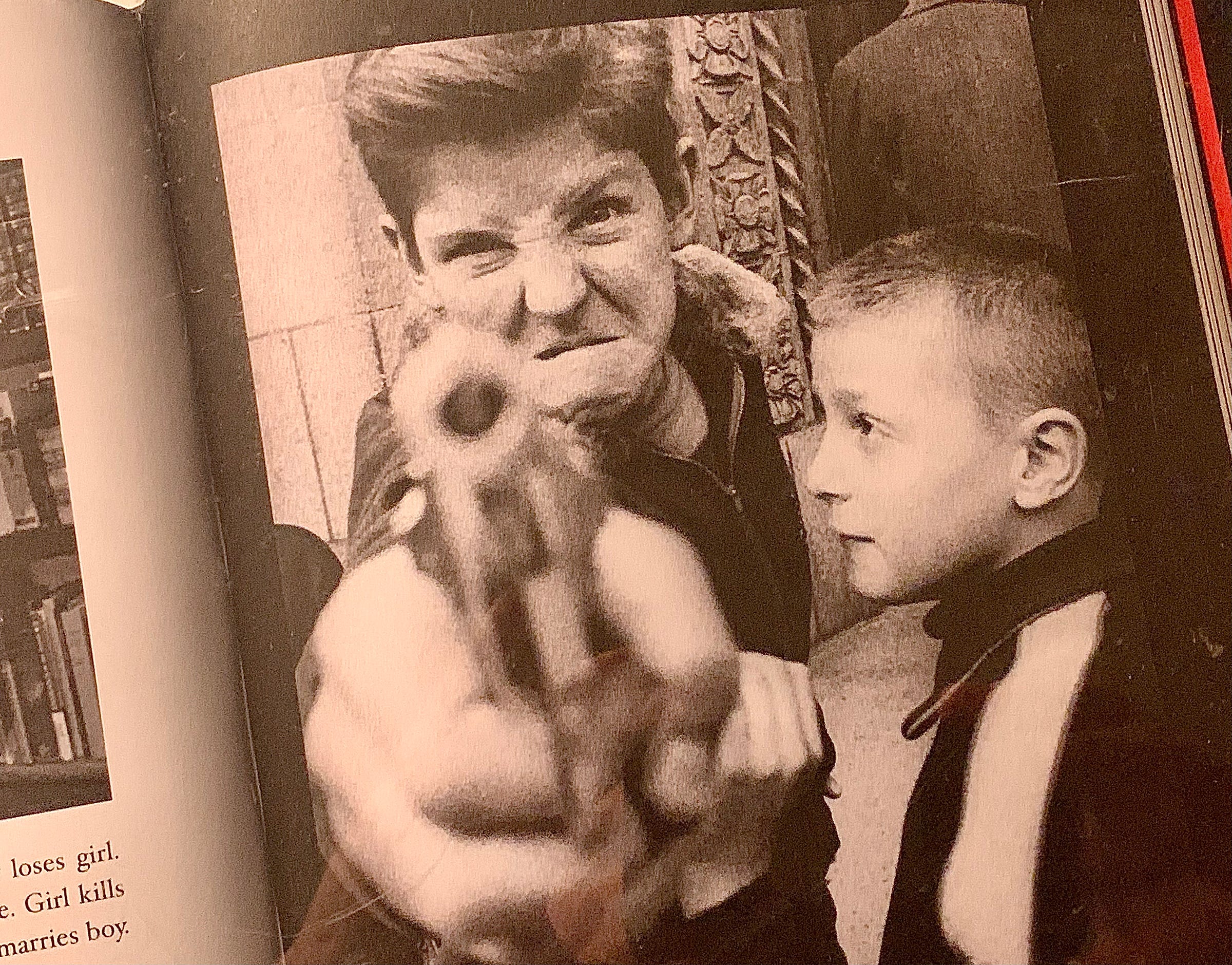 Young boy pointing gun at camera with younger boy watching